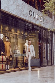 Elegant woman walks by Gucci store in Istanbul, shopping luxury fashion items.