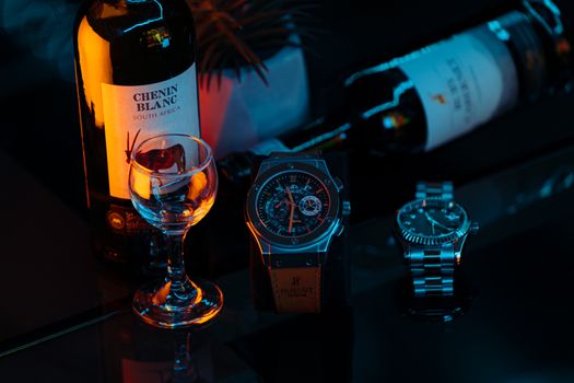 Elegant arrangement of wine and wristwatches with artistic lighting.