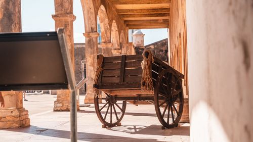 Free Rustic wooden cart displayed amidst historical stone columns outdoors. Stock Photo