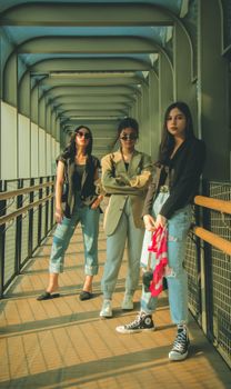 Three stylish young women pose confidently in urban Jakarta showing contemporary fashion trends.