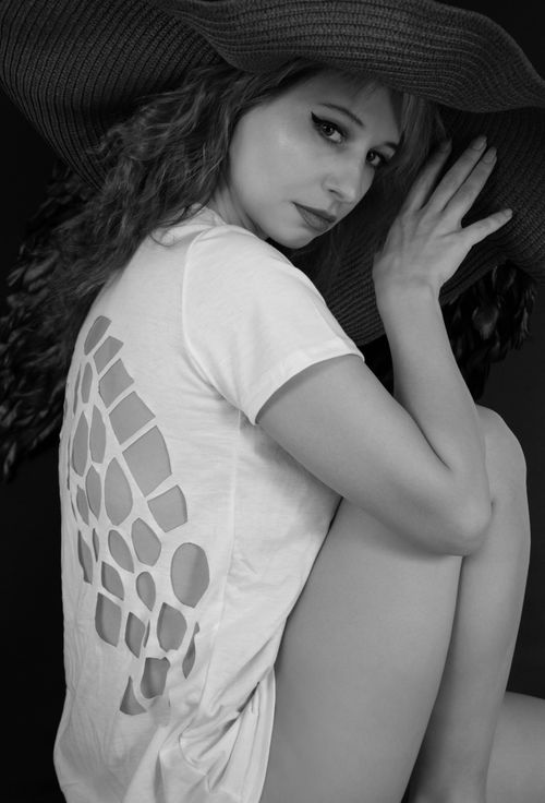 Free Black and white image of a woman in a stylish hat and white t-shirt with cutouts. Stock Photo