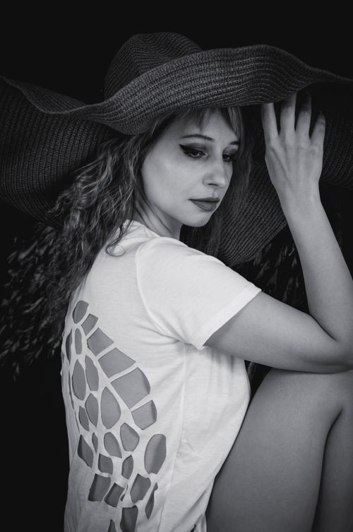 Free Stylish black and white portrait of a woman in a round hat and cut-out t-shirt. Stock Photo