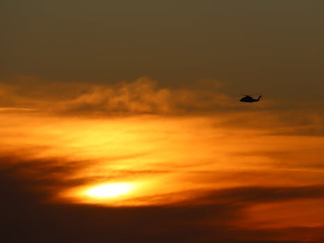 A silhouette of a helicopter flying against a golden sunset sky in Los Angeles.