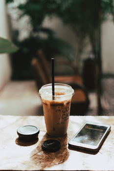 A refreshing iced coffee next to a smartphone in a cozy Ho Chi Minh café.