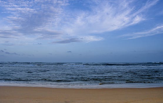 Peaceful beach and ocean view at Puri, India showcasing waves and cloudy sky.