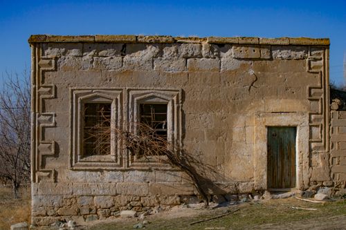 Free A vintage stone structure with weathered windows and door, showcasing historic architecture outdoors. Stock Photo