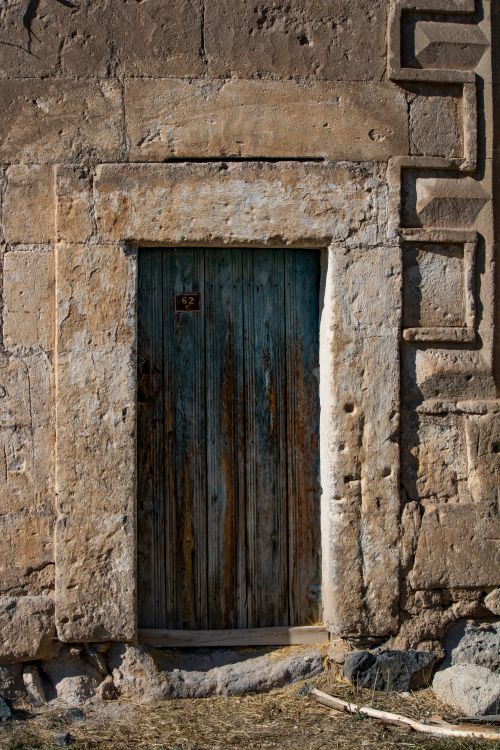 Free A rustic stone doorway showcasing weathered wooden door with historical charm. Stock Photo