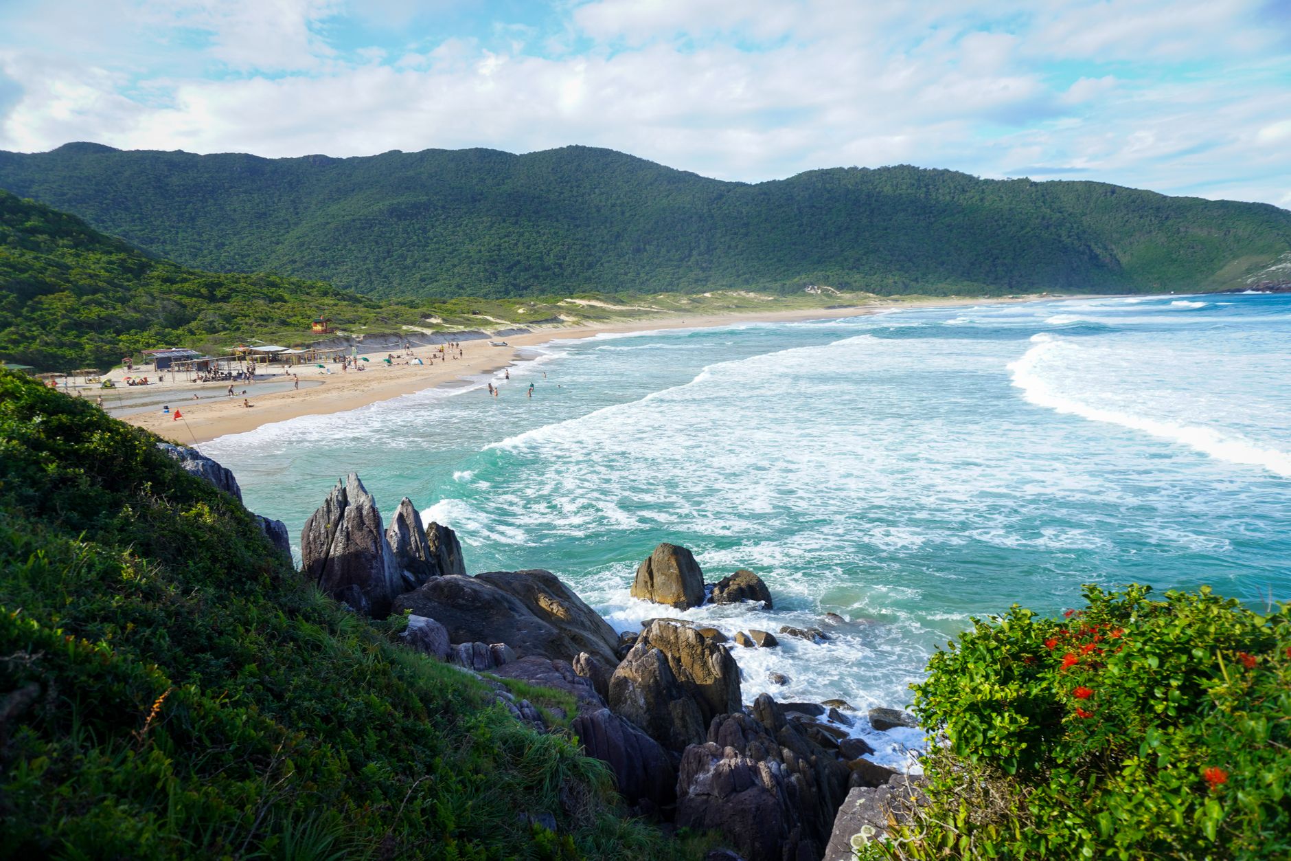Beautiful Brazilian coast with waves, rocks, and lush green mountains.