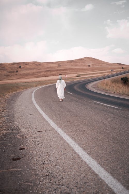 Person in White Dress Walking along Empty Street 