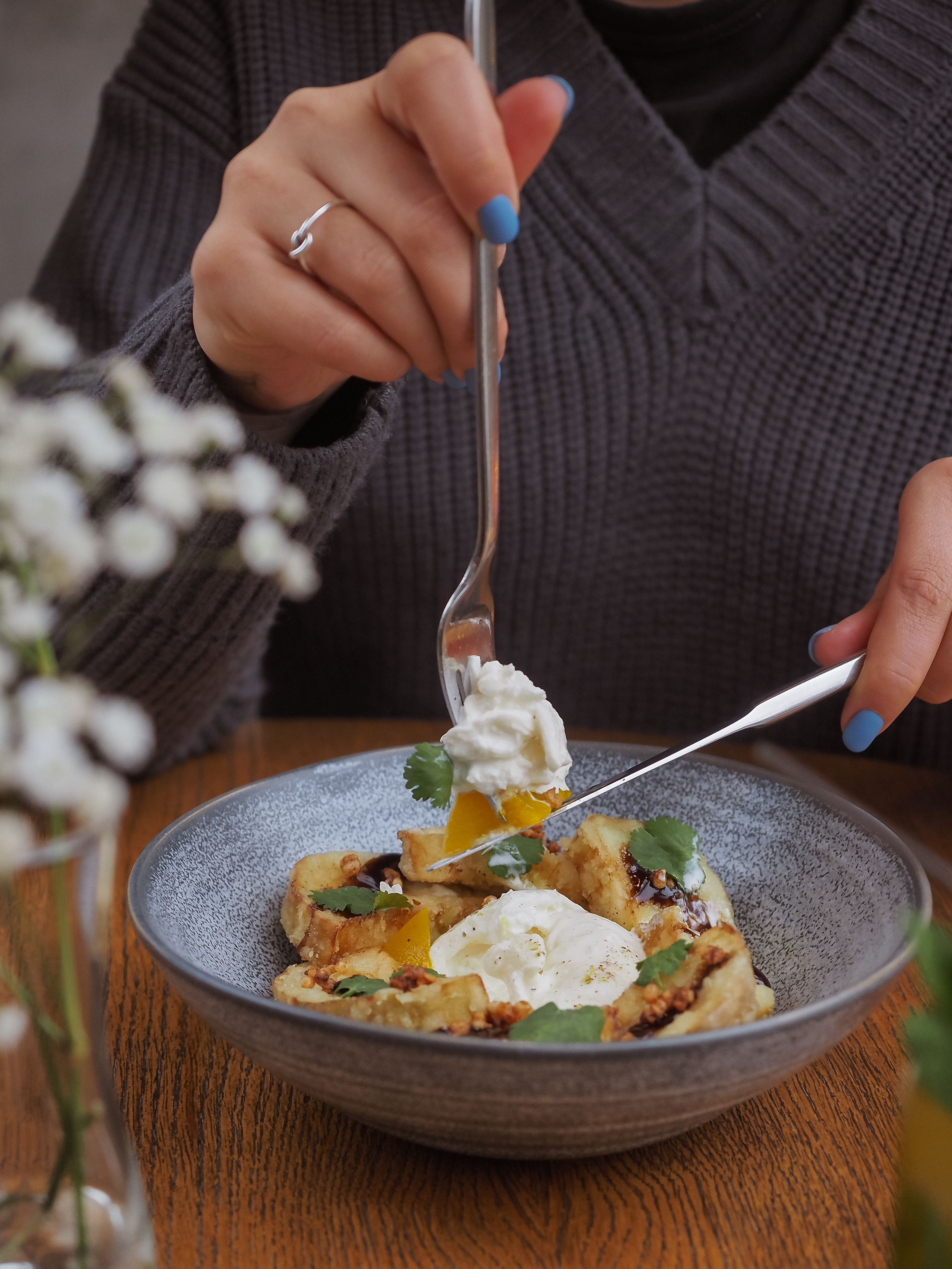 A close-up of a person enjoying a warm meal with fresh ingredients in a cozy setting.