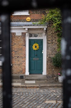 A picturesque brick facade with a green door and sunflower wreath in London, UK.