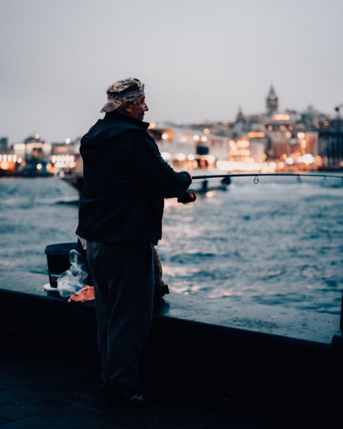 Free A lone fisherman casts his line by the Bosphorus in Istanbul at dusk, capturing the city's serene evening atmosphere. Stock Photo