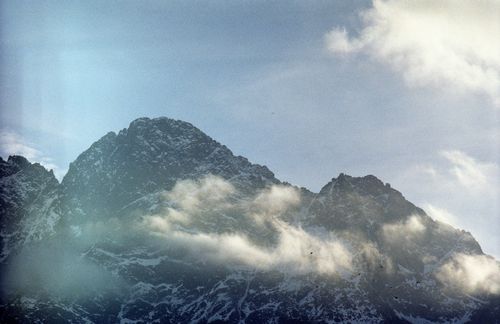 Free A stunning view of rugged mountain peaks enveloped by clouds on a sunny day. Stock Photo