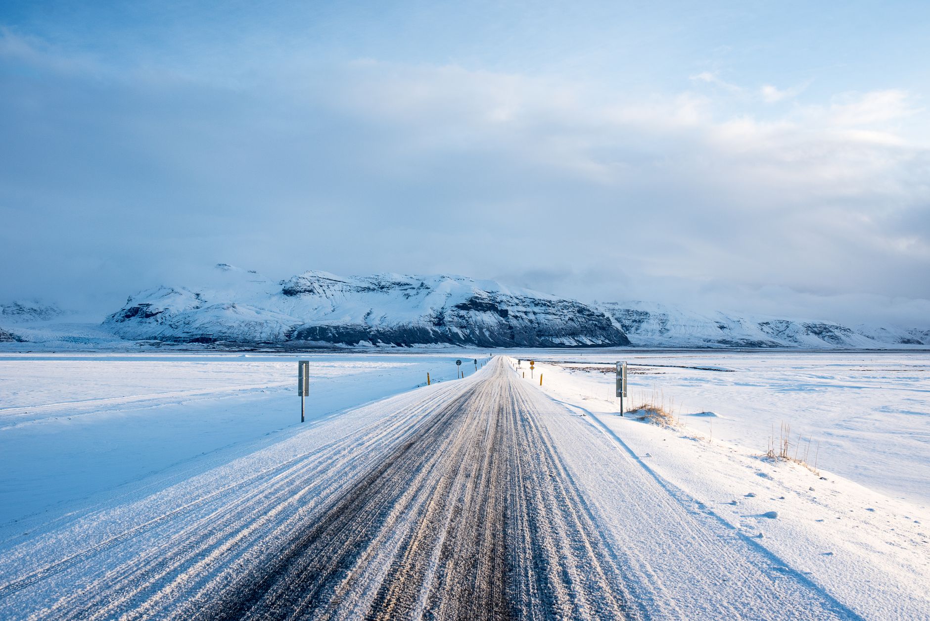 Snow-covered road leading to mountains in Vík í Mýrdal, Iceland. Scenic winter view.