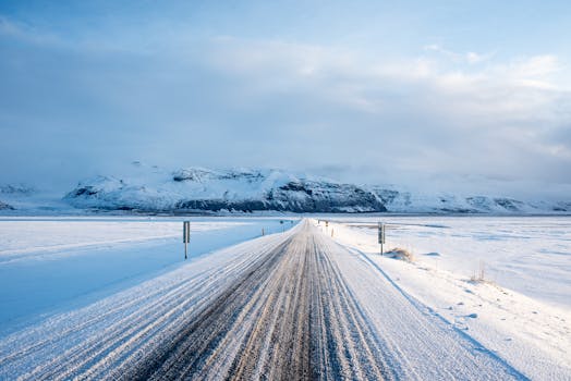 Snow-covered road leading to mountains in Vík í Mýrdal, Iceland. Scenic winter view.