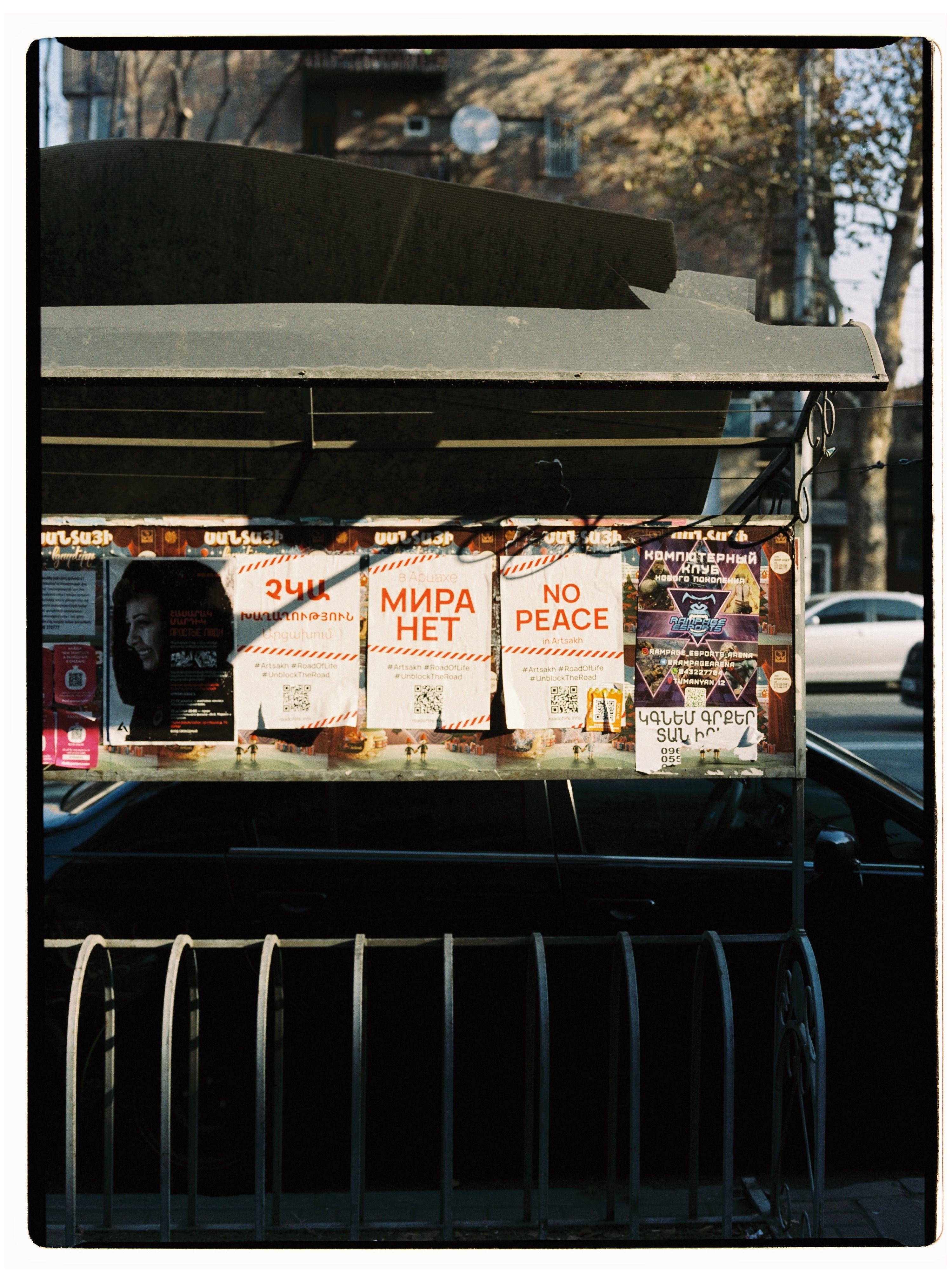 Colorful posters and leaflets displayed on a street board in Yerevan, Armenia, conveying various messages.