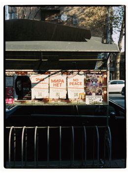 Colorful posters and leaflets displayed on a street board in Yerevan, Armenia, conveying various messages.