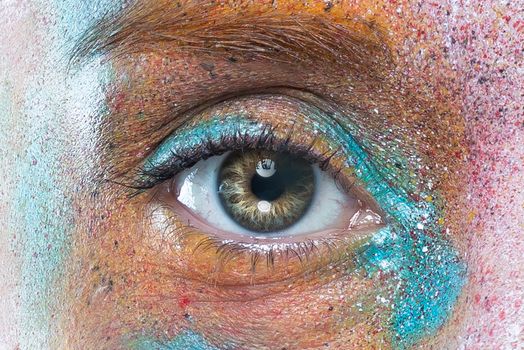 A detailed close-up of an eye with colorful artistic makeup, showcasing texture and glitter.