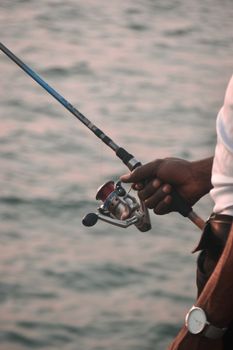 A close-up view of a person holding a fishing rod over water in Lagos, Nigeria.