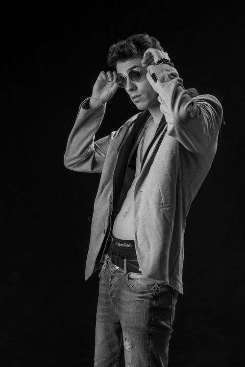 Free Monochromatic portrait of a fashionable man adjusting sunglasses with attitude. Stock Photo