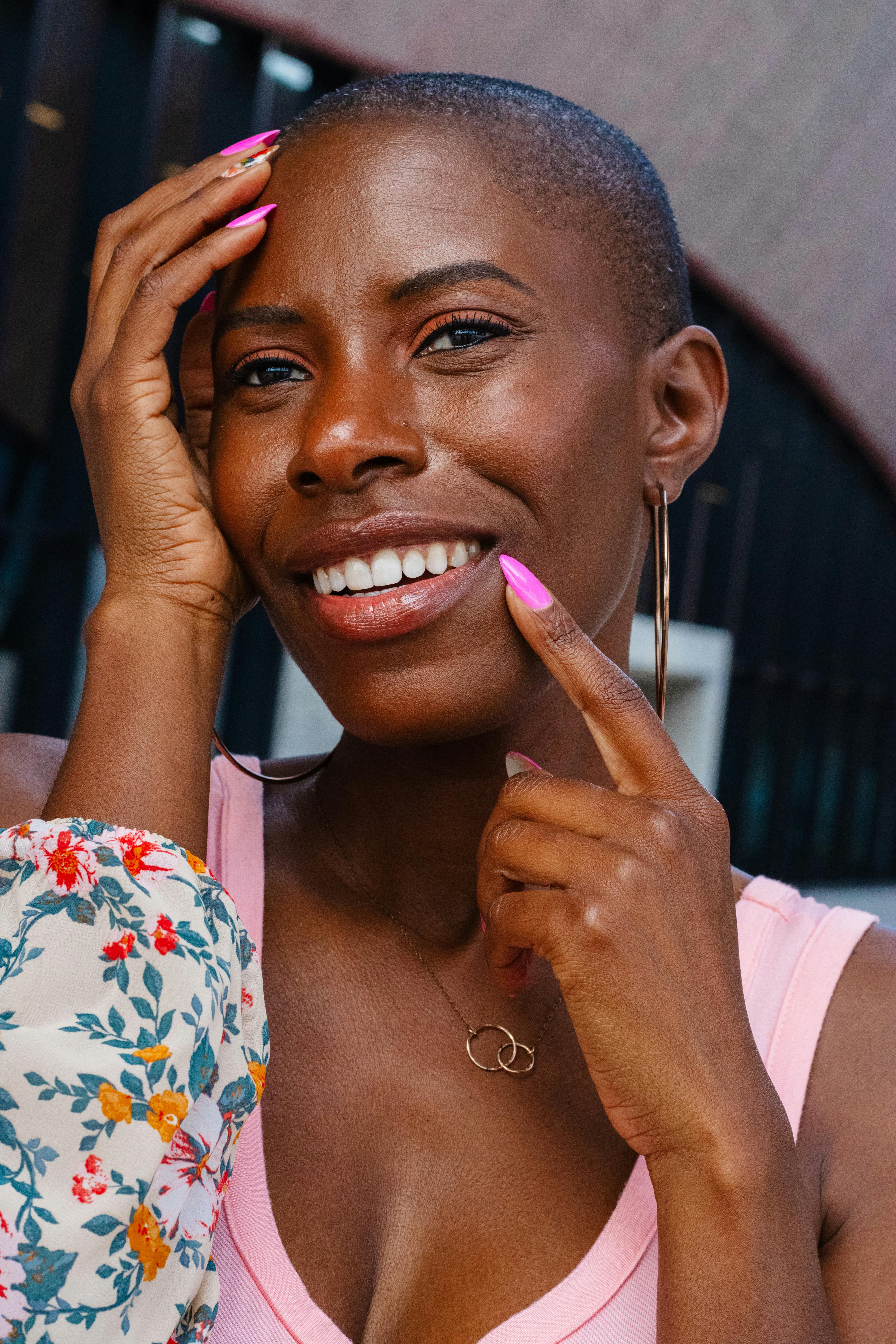 一位剃着光头微笑的非洲女性的迷人肖像，展示了户外的优雅和风格