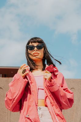 Free Fashionable woman in pink jacket and sunglasses enjoying a sunny day outdoors. Stock Photo