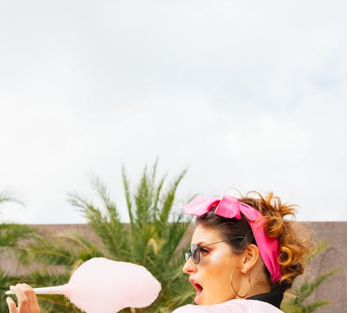 A Woman Wearing a Pink Headband while Holding a Cotton Candy