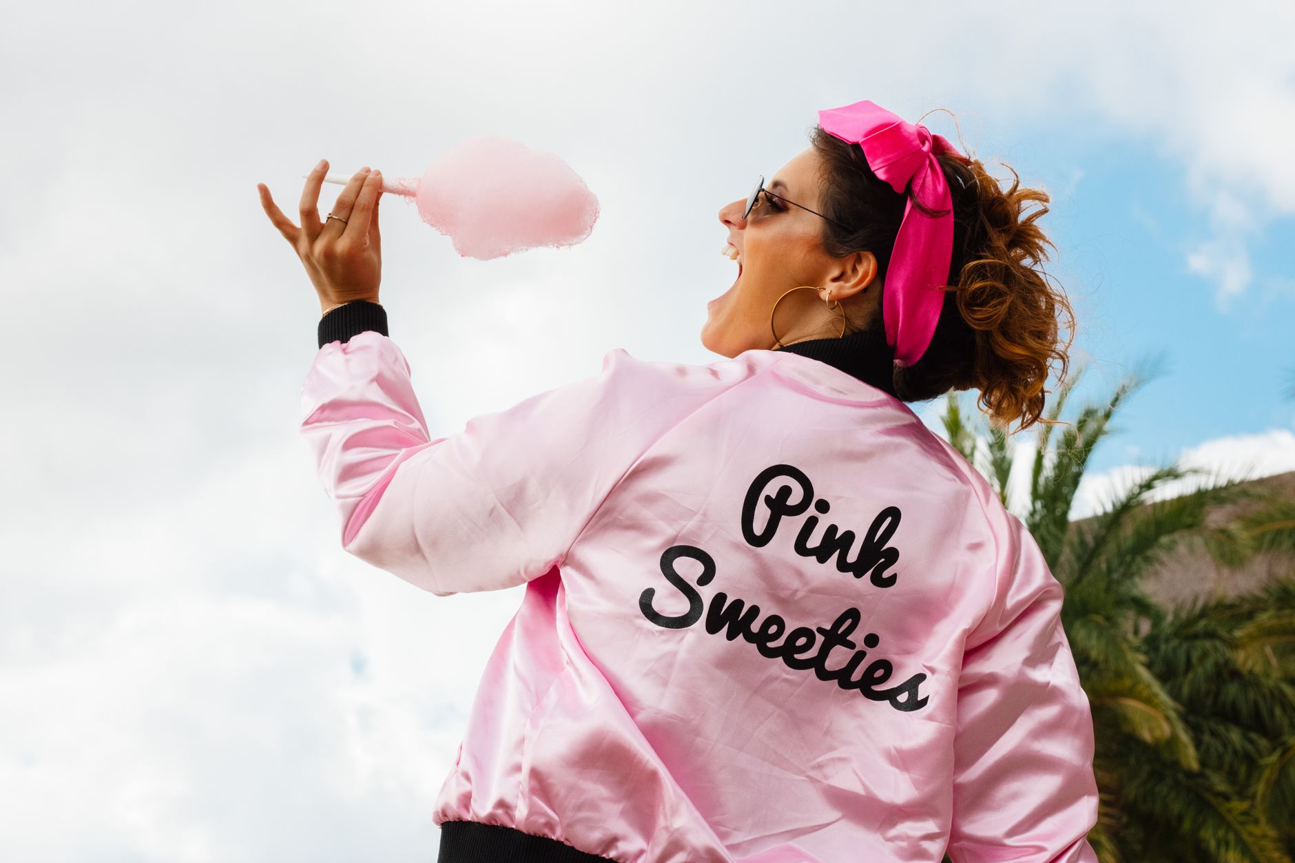 candy floss station events cairo — Back view of a woman in a pink jacket holding cotton candy outdoors.