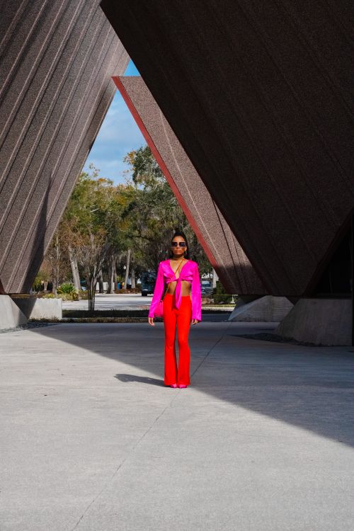 Free Stylish woman posing in vibrant outfit against geometric architecture, showcasing modern fashion. Stock Photo