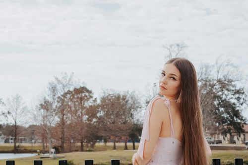 Free A young woman with long hair glances back outdoors, offering a serene and contemplative vibe. Stock Photo