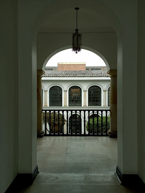 Free View through a classic archway showcasing colonial architecture with balconies and terraces. Stock Photo