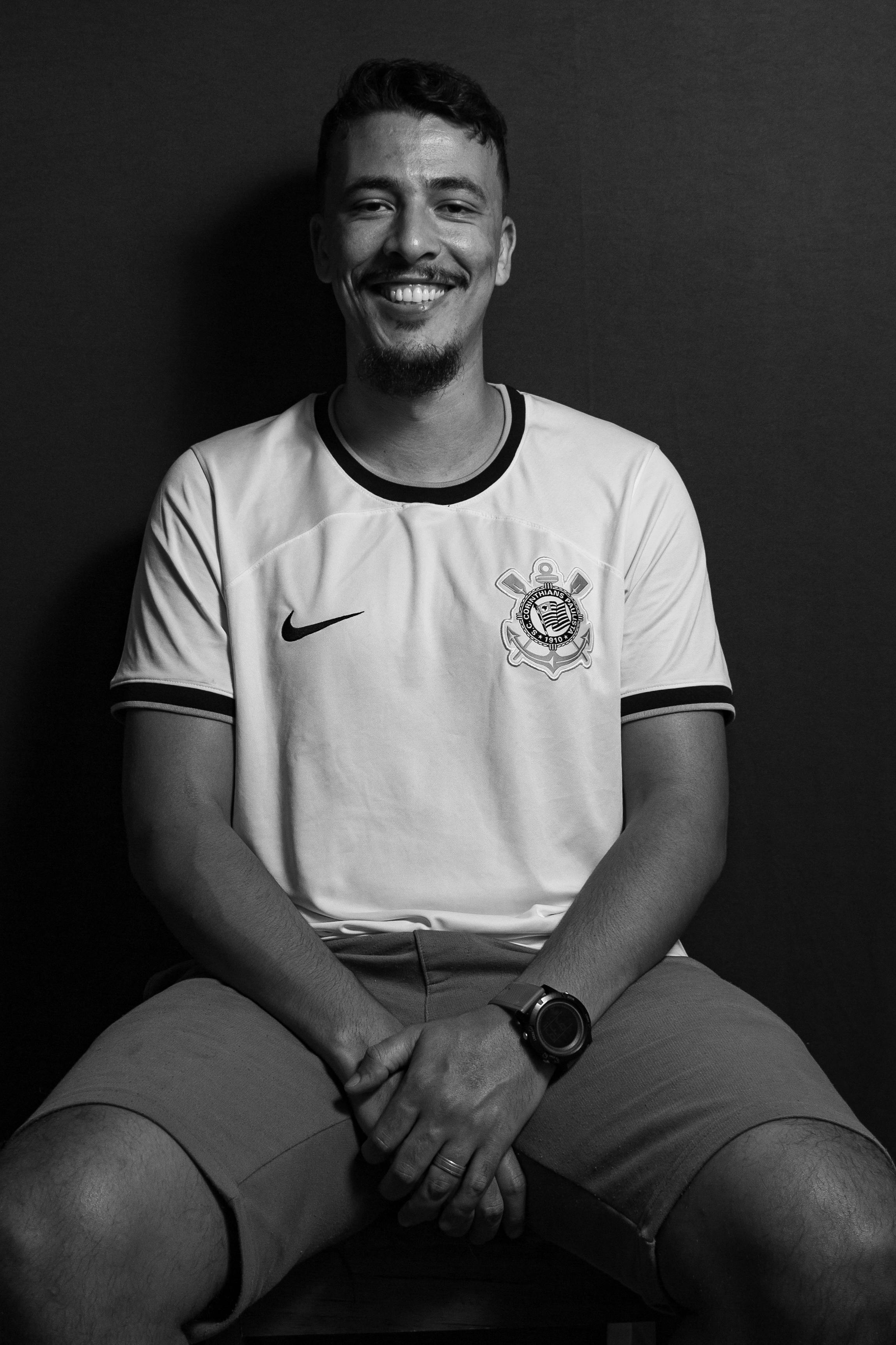 Portrait of a smiling man with a goatee wearing a sports jersey, captured in a monochrome setting.