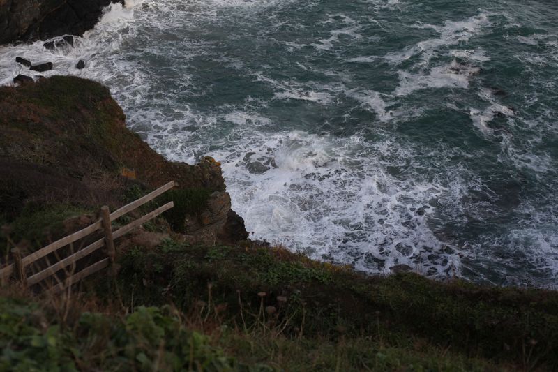 A breathtaking aerial view of the rugged Cornish coastline with crashing waves.