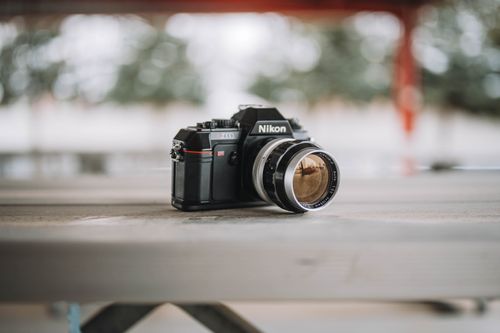 Free Classic Nikon film camera resting on a rustic wooden surface, evoking nostalgia. Stock Photo