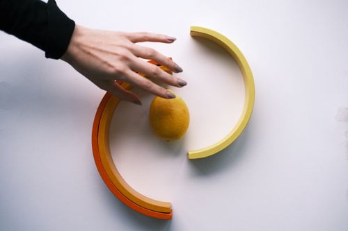 Free Creative arrangement of a hand reaching for a lemon on a minimalist background. Stock Photo