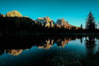 日落时分拍摄的这座山间湖泊风景优美，映照着引人注目的山峰和郁郁葱葱的树木