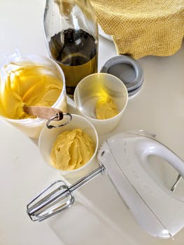 A high-angle view of cream being mixed with olive oil bottles and kitchen tools, perfect for cooking projects.