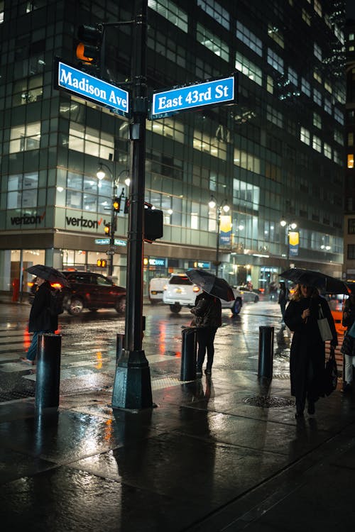 People with Umbrellas on Night City Street