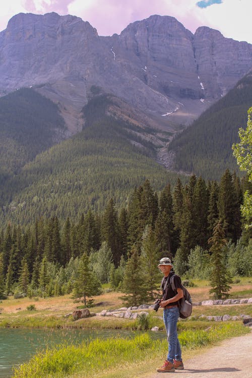 Man on Lakeshore near Forest in Mountains