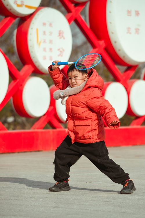 Free Child having fun playing badminton outside during winter, dressed in warm outerwear. Stock Photo