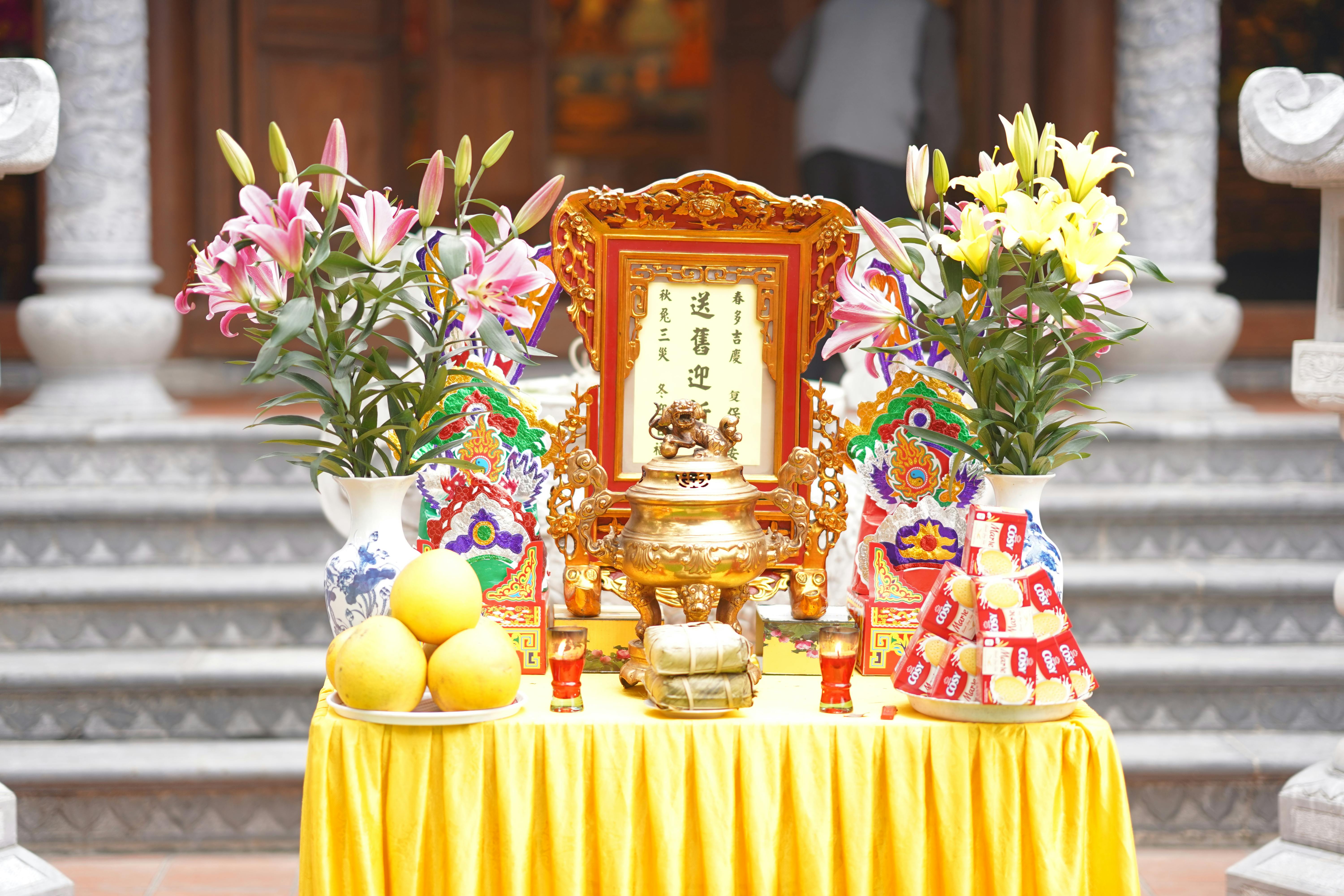 Colorful altar setup with flowers, fruits, and ornate decorations on a yellow cloth.