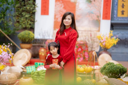 A mother and daughter in red dresses celebrating Lunar New Year with decorations.