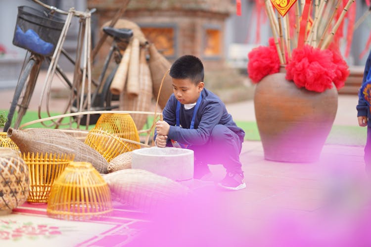 Boy Crouching Near Bowl And Bags