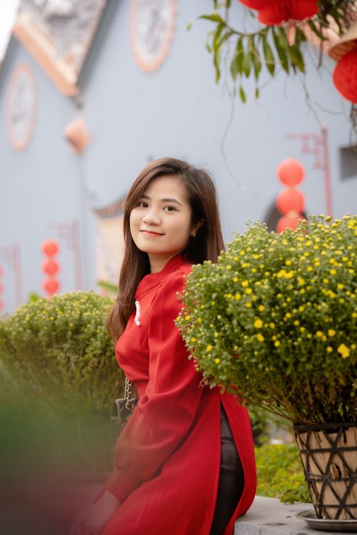 Free Woman in traditional red dress smiling amidst festive decorations and yellow flowers. Stock Photo