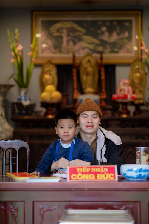 Free Asian father and son sitting together indoors in a serene traditional cultural setting. Stock Photo