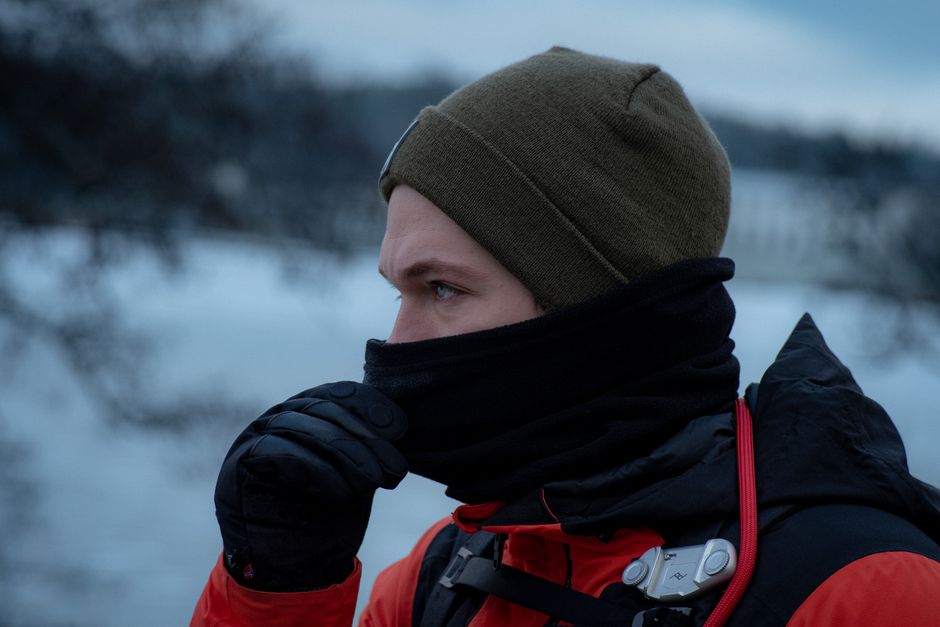 Profile of a man in winter attire with obscured face outdoors.