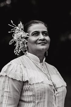 一幅黑白肖像，描绘了一位身着传统服装、头戴花卉假发的优雅女性