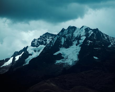 A scenic view of majestic snow-covered mountains under a moody sky.