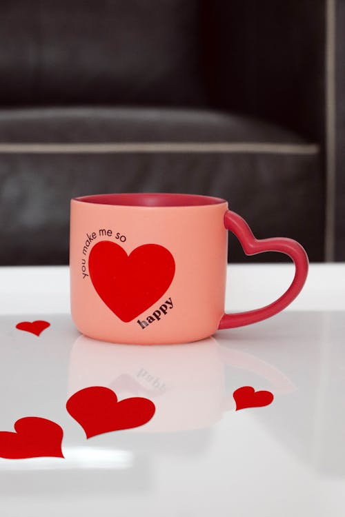 A Pink Cup with Illustration of a Heart and a Heart Shaped Handle 