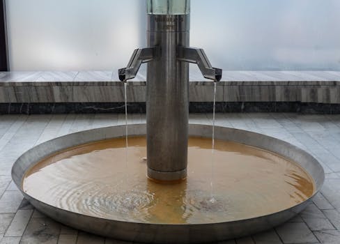 Close-up of a modern metal fountain in Karlovy Vary spa, Czech Republic, showcasing flowing thermal water.